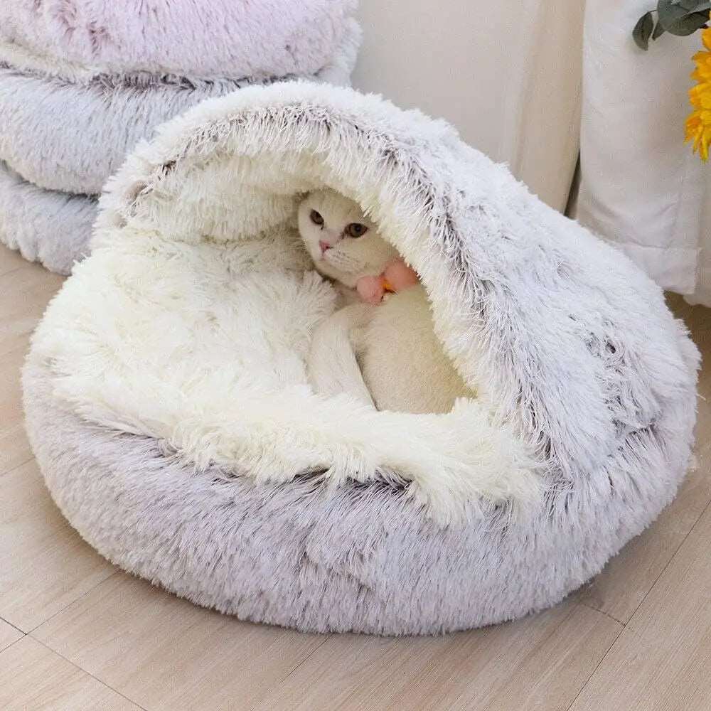 Chat confortablement installé dans un lit rond en peluche beige.