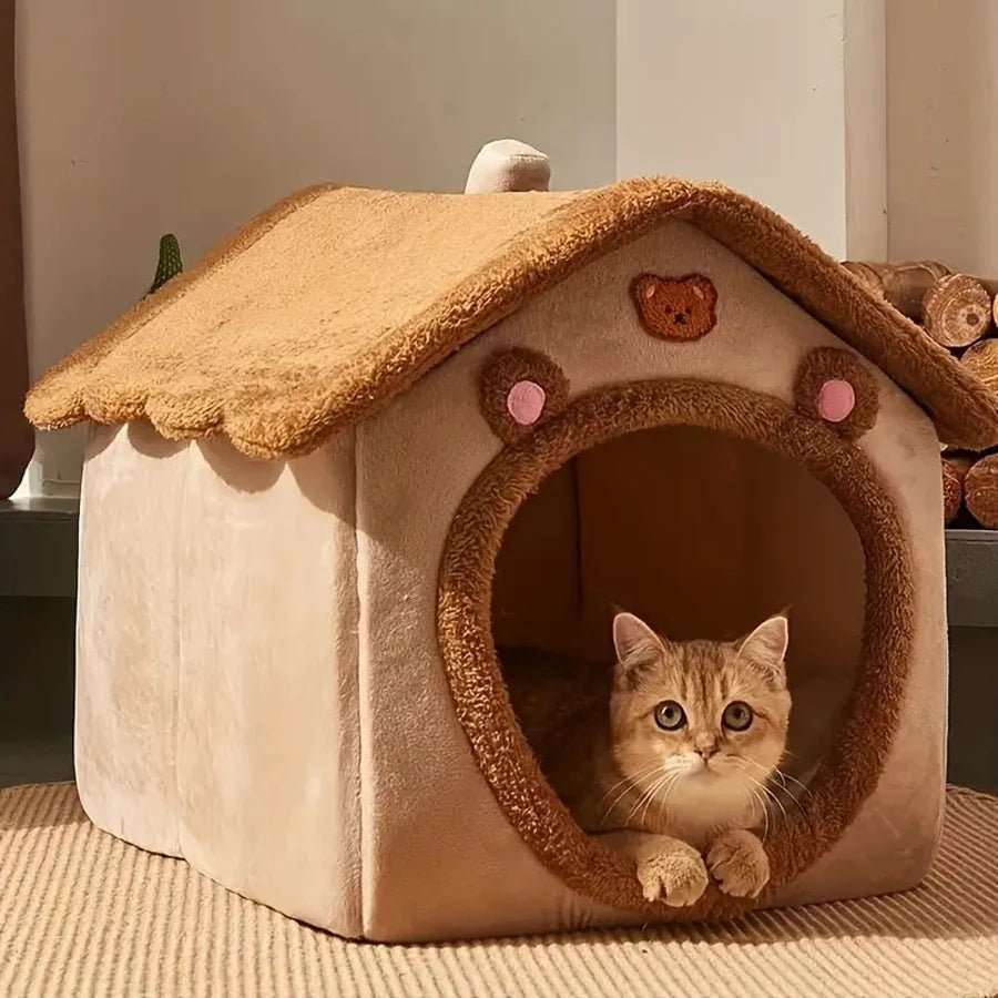 Chat roux dans niche douillette en forme de maison ours.